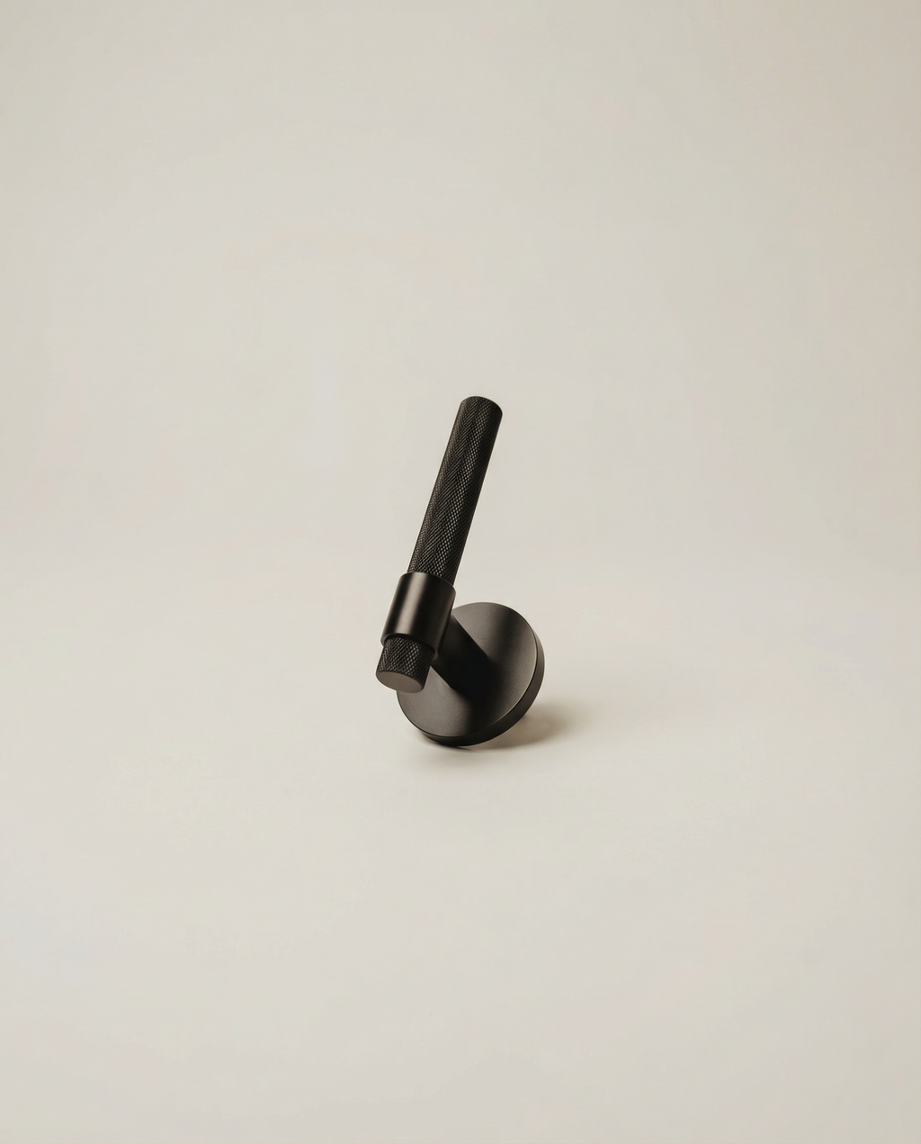The Bauhaus Pull - matte black solid brass door lever with knurled grip on neutral background