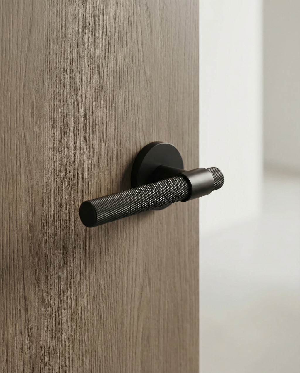 The Bauhaus Pull matte black brass door lever installed on oak wood door - luxurious architectural hardware